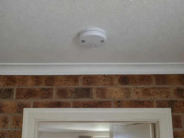 Ceiling smoke alarm above a brick wall and doorway in a home interior in Cameron Park